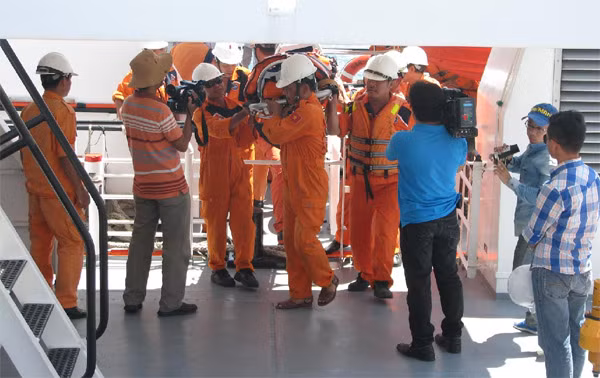 Các nhân viên cứu hộ trên tàu RAR 274 đưa các ngư dân gặp nạn của QNa 92647 TS lên bờ.