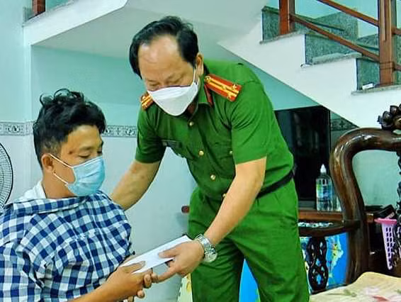 Thượng tá Pham Minh Mẫn, trưởng Công an quận Sơn Trà (TP Đà Nẵng) cùng lãnh đạo UBND quận Sơn Trà trao hỗ trợ anh Mai Quốc Long 25 triệu đồng. (Ảnh CAST)
