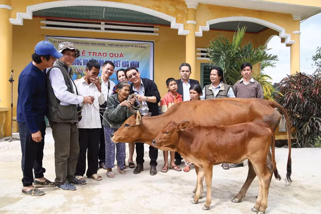 Nhà báo Vũ Công Điền và các nhà tài trợ tặng bò cho người nghèo.