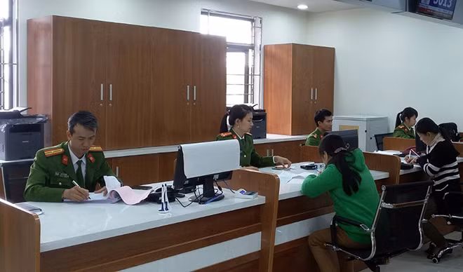 Thiếu tá Mai Văn Hiển (bìa trái) giúp người dân làm thủ tục hành chính.