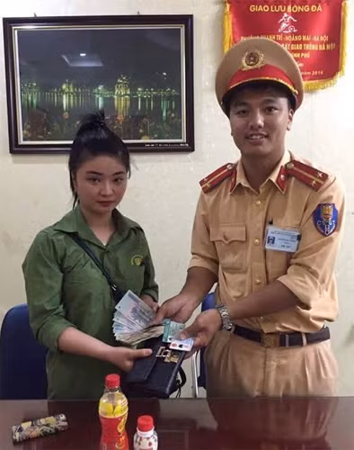 Cán bộ Đội CSGT số 1 Công an TP Hà Nội trả lại tài sản nhặt được cho người dân.