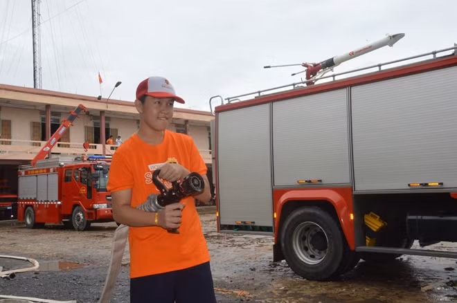 Một em học sinh rất thích thú, khi lần đầu tiên được cầm vòi cứu hỏa.