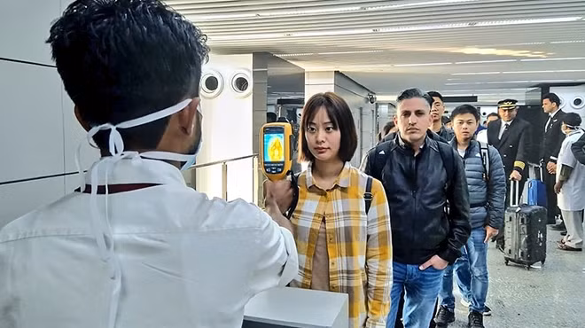 Nhân viên y tế đo thân nhiệt tại một nhà ga sân bay. Ảnh: ITN