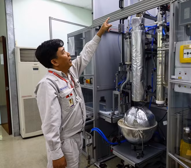 Cán bộ phòng thí nghiệm đang trình bày về nguyên lý hoạt động của một máy lọc dầu thu nhỏ.