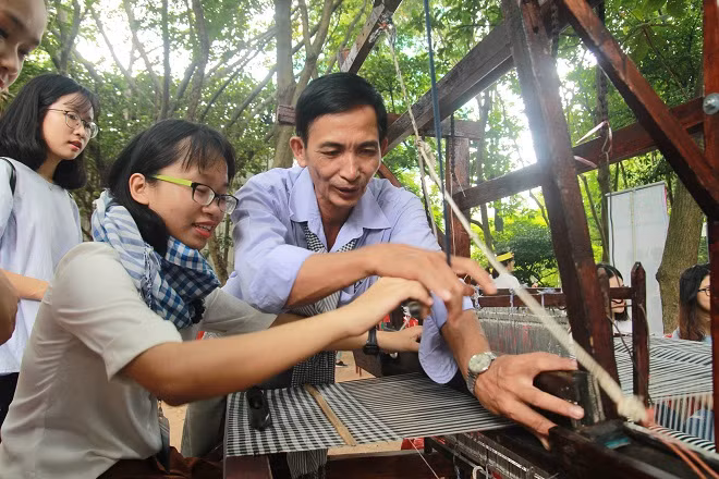Nghệ nhân hướng dẫn các em nhỏ cách dệt khăn rằn.