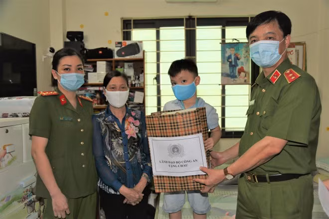 Thứ trưởng Nguyễn Duy Ngọc tặng quà cho mẹ con Đại úy Bùi Thị Lan Hương và gia đình.