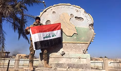 Một binh sĩ Iraq giương cờ trên trụ sở hành chính ở Ramadi, Iraq, ngày 28-12.