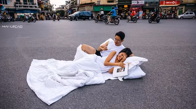 Hình ảnh đôi bạn mang chăn gối chụp ảnh cưới giữa đường.