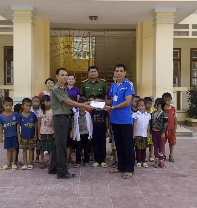 Đại diện Công an huyện Mường La trao 5 triệu đồng do anh Lưu Văn Long, bạn đọc Báo CAND ủng hộ cho thầy trò Trường Tiểu học Nặm Păm.