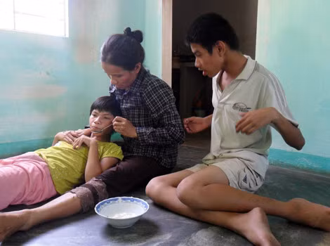 Chị Minh chăm sóc hai đứa con bị bệnh bại não trước khi đi làm.
