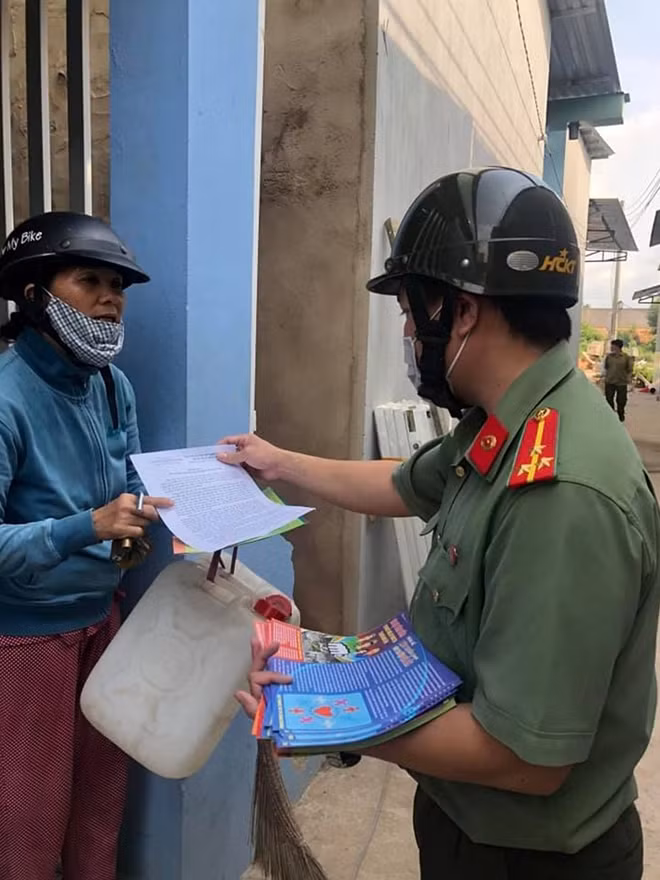 Cán bộ Công an phát tờ rơi tuyên truyền phòng chống tội phạm và dịch COVID-19
