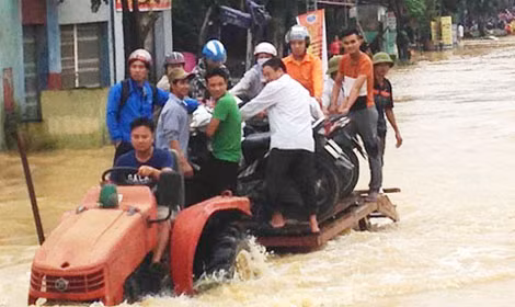 Tại Thanh Hóa, người dân dùng xe công nông để vận chuyển người và phương tiện qua đoạn ngập. Ảnh: L.H.