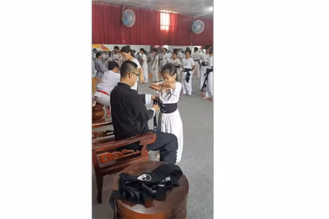 Võ sư Nam Anh Kiệt thắt đai lưng cho một cháu bé trong nghi thức nhập môn Vịnh Xuân Chính thống phái.