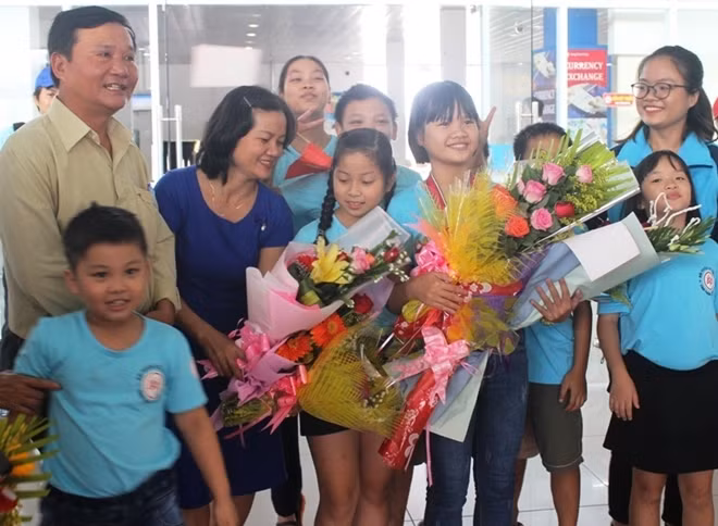 Kỳ thủ nhí Võ Nguyễn Quỳnh Như (đứng thứ 4 từ phải sang trái) được người thân, thầy cô giáo tặng hoa chúc mừng khi trở về Huế.