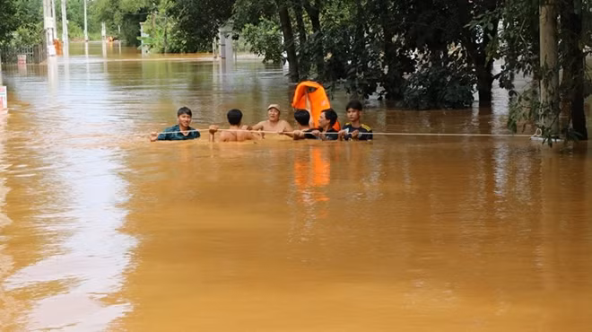 Trong dòng nước lũ chảy xiết, lực lượng cứu hộ phải rất vất vả bám vào từng gốc cây, cột điện để đưa xuồng cứu hộ tiếp cận các ngôi nhà có người bị kẹt