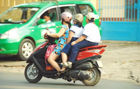 Thậm chí nhiều phụ huynh chở ba, chở bốn nhưng không đội MBH cho trẻ. (chụp tại cổng Trường tiểu học Trần Văn Ơn).