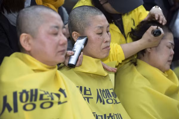 Những thành viên của gia đình nạn nhân thảm họa phà Sewol cạo đầu tại quảng trường Gwanghwamun thành phố Seoul ngày 2/4/2015. Nhiều người nhà nạn nhân đã tập trung tại đây biểu tình kêu gọi trục vớt phà Sewol và tìm ra sự thật đằng sau thảm họa này.