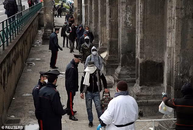 Những người vô gia cư xếp hàng chờ đợi phát thực phẩm tại Italia. Ảnh: Reuters