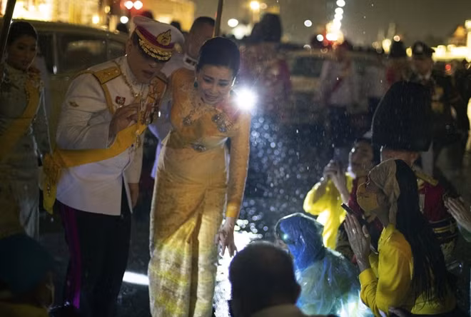 Nhà vua Thái Lan cùng hoàng hậu chào đón người dân dưới mưa. Ảnh: AP