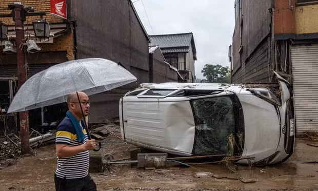 Chiếc xe ô tô bị nước lũ cuốn trôi, lật ngang trên đường phố. Ảnh: Getty
