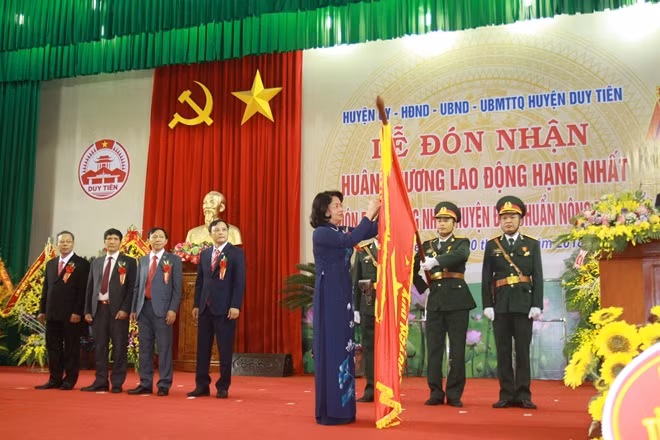 Phó Chủ tịch nước Đặng Thị Ngọc Thịnh gắn Huy hiệu Anh hùng Lao động lên lá cờ truyền thống của huyện Duy Tiên.