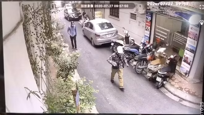 Hai đối tượng mặc áo chống nắng, đeo khẩu trang, đội mũ bảo hiểm đi bộ đến khu vực ngân hàng.