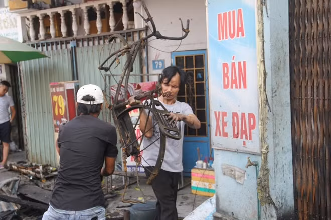 Những chiếc xe đạp điện bị cháy còn trơ khung được đưa ra khỏi cửa hàng sau vụ hỏa hoạn.