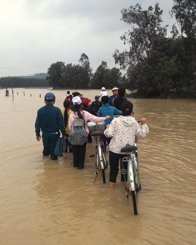 Nước lụt gây chia cắt nhiều tuyến đường ở huyện Sơn Tịnh. Dân quân địa phương phải túc trực và hướng dẫn người dân qua lại.
