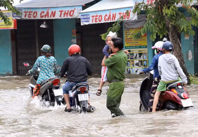 Hình ảnh cán bộ Công an bồng cháu bé trên đường Cách Mạng Tháng 8, qua khu vực ngập nước gây xúc động.