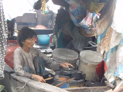 Bà Hai cặm cụi nấu ăn trong chiếc thuyền mục ruỗng.