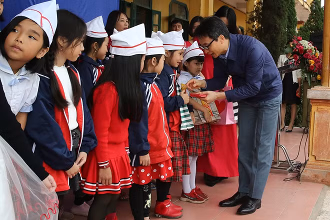 Phó Thủ tướng Vũ Đức Đam "mừng tuổi sách" và lì xì cho các em học sinh trường tiểu học Dạ Trạch. Ảnh: VGP/Đình Nam