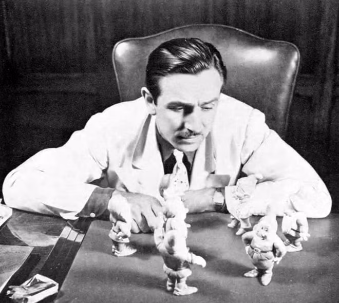 Walt Disney bên những bức tượng chú lùn.