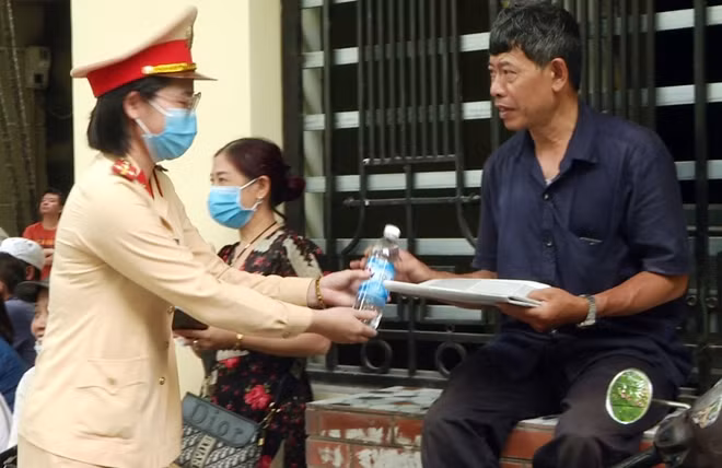 Phụ huynh học sinh nhận nước từ nữ Cảnh sát giao thông.
