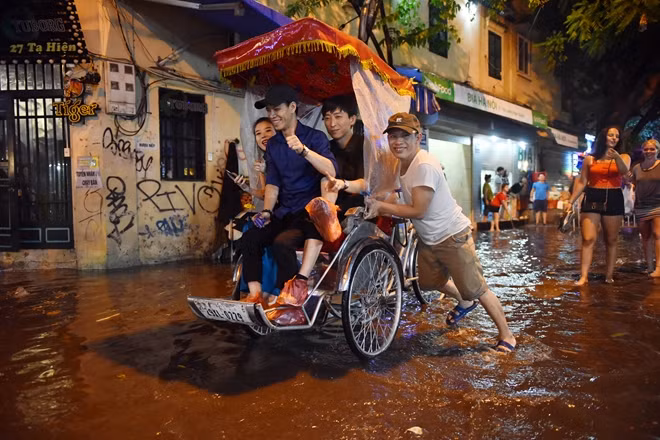 Một dịch vụ tự phát xuất hiện ngay sau cơn mưa lớn đêm qua. Dịch vụ chở khách qua đoạn đường ngập ở phố cổ bằng xích lô với mức giá có thể lên tới 500.000 đồng/lượt đối với khách nước ngoài.