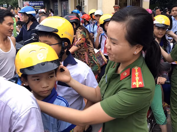 Cán bộ Công an tặng mũ bảo hiểm đúng chuẩn, miễn phí cho học sinh.
