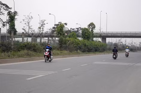 Người điều khiển xe gắn máy vừa di chuyển trên đường gom vừa sử dụng điện thoại.