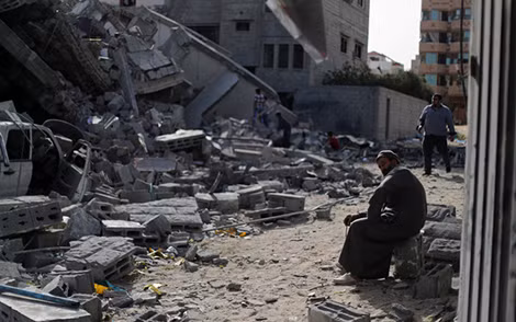 Người đàn ông Palestine ngồi trên đống đổ nát gần một tòa nhà bị phá hủy trong các đợt không kích của Israel tại thành phố Gaza.