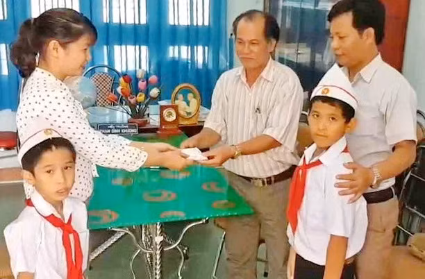 Đại diện Trường Tiểu học số 1 Phước Hiệp cùng hai nam sinh chuyển giao tài sản nhặt được cho công an địa phương. Ảnh : Bảo Thoa
