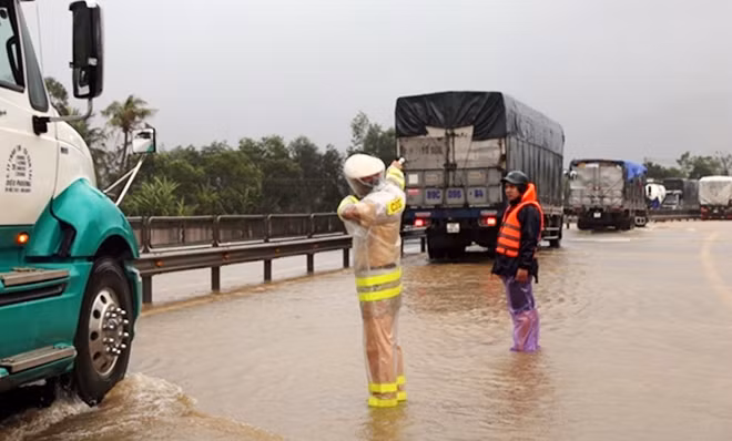 Bám mặt đường quốc lộ 1A ngập lụt, hướng dẫn cho từng chiếc xe qua.