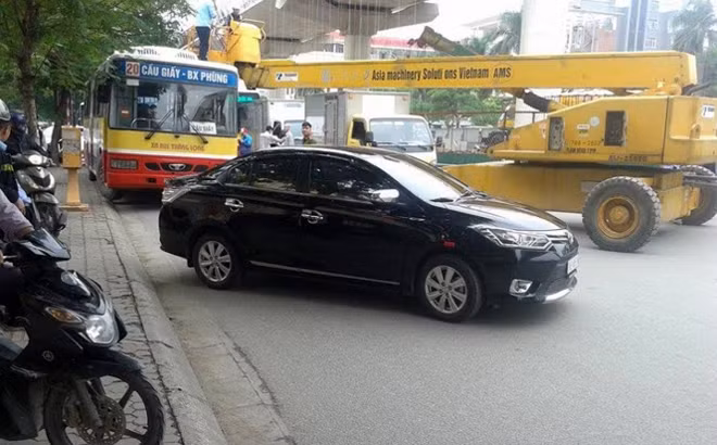 Xe máy và ô tô con buộc phải lách lên vỉa hè để vượt qua sự cố giao thông.