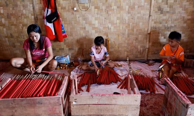 Alen Lenni (trái) và hai con sản xuất các que hương lớn trong xưởng tại gia ở ngoại ô thủ đô Jakarta của Indonesia hôm 10/2.