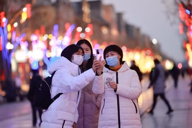 Người dân vui vẻ chụp hình selfie trên đường phố Bắc Kinh, vẫn đeo khẩu trang để phòng dịch COVID-19.