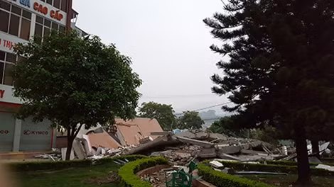 Chiếc máy xúc của công trình xây dựng gần đó bị đè trong đất đá.