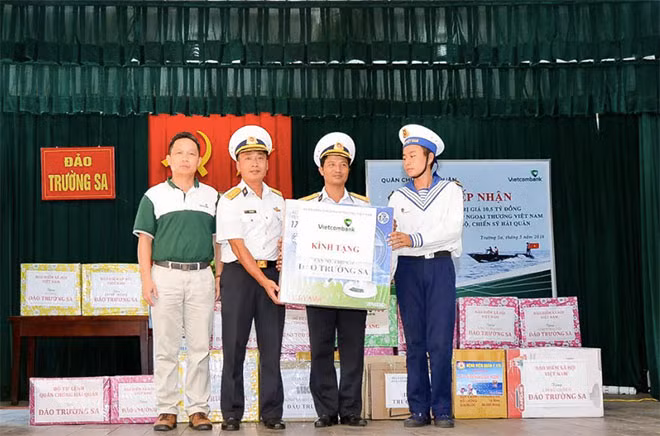 Đồng chí Nguyễn Mạnh Hùng – UV Ban thường vụ Đảng ủy, UV HĐQT Vietcombank (ngoài cùng bên trái) trao tượng trưng 01 trong 54 thùng quà tặng cho cán bộ, chiến sỹ và nhân dân thị trấn Trường Sa trên đảo Trường Sa.