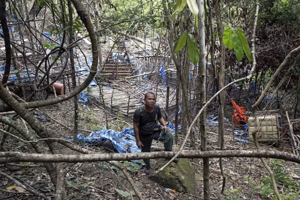 Một cảnh sát đứng giữa một trại bỏ hoang của bọn buôn người tại Bukit Wang Burma miền bắc Malaysia gần biên giới với Thái Lan. Ảnh: Reuters.
