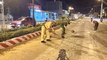 Công an cùng người dân thu dọn đá dăm rơi vãi trên mặt đường lộ