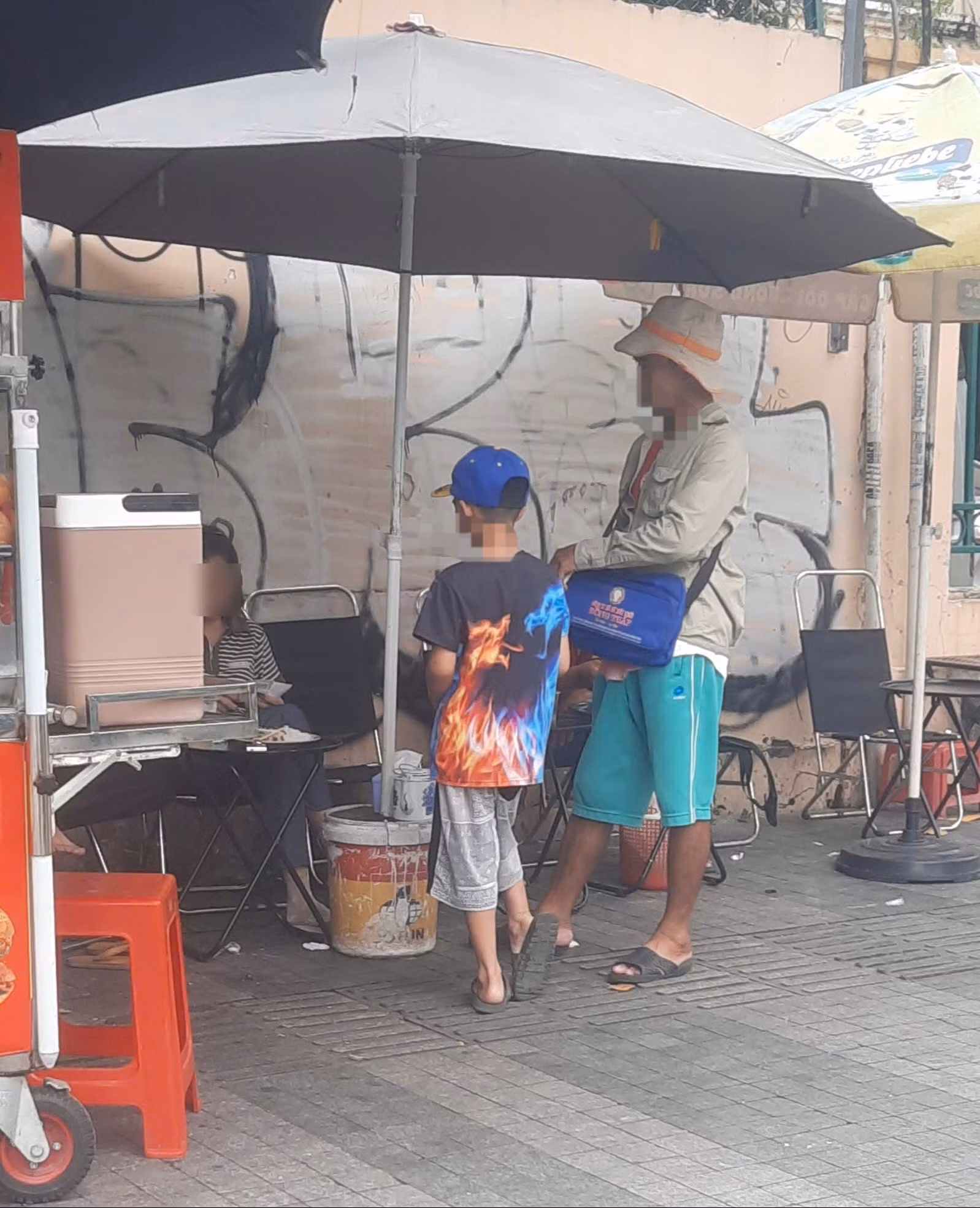 Một em nhỏ được một đàn anh dắt đi bán vé số khu vực Hồ Con Rùa, TP Hồ Chí Minh