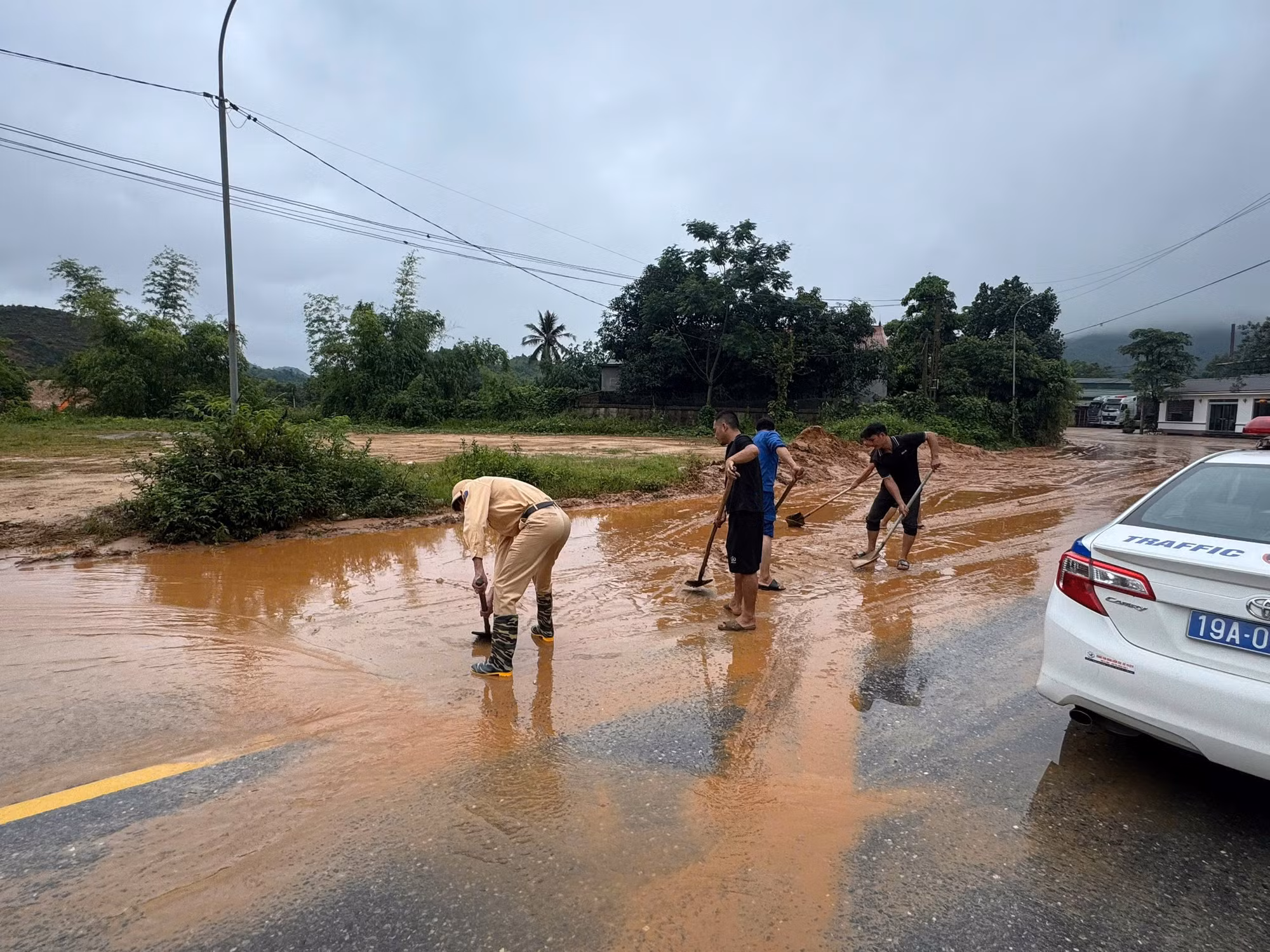 Tổ công tác của Đội CSGT đường bộ số 2, Phòng CSGT Công an tỉnh Phú Thọ phối hợp với người dân dùng xẻng dọn dẹp phần đất, đá rơi trên mặt đường.