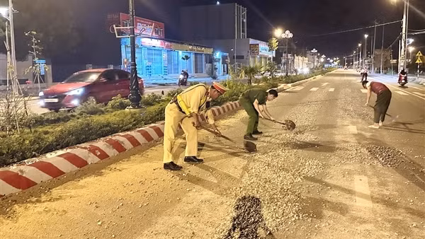 Công an cùng người dân thu dọn đá dăm rơi vãi trên mặt đường lộ