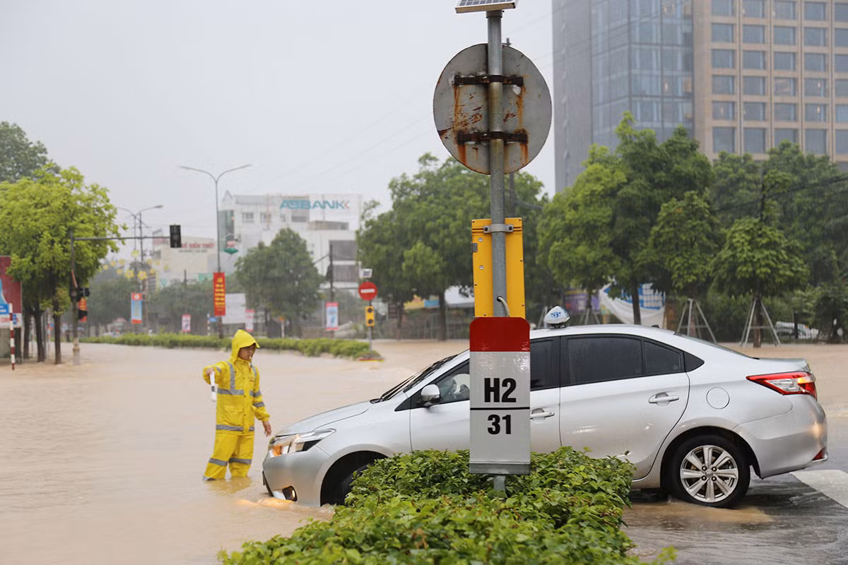 Hỗ trợ người dân đi qua các đoạn đường bị ngập úng sau trận mưa lớn -3